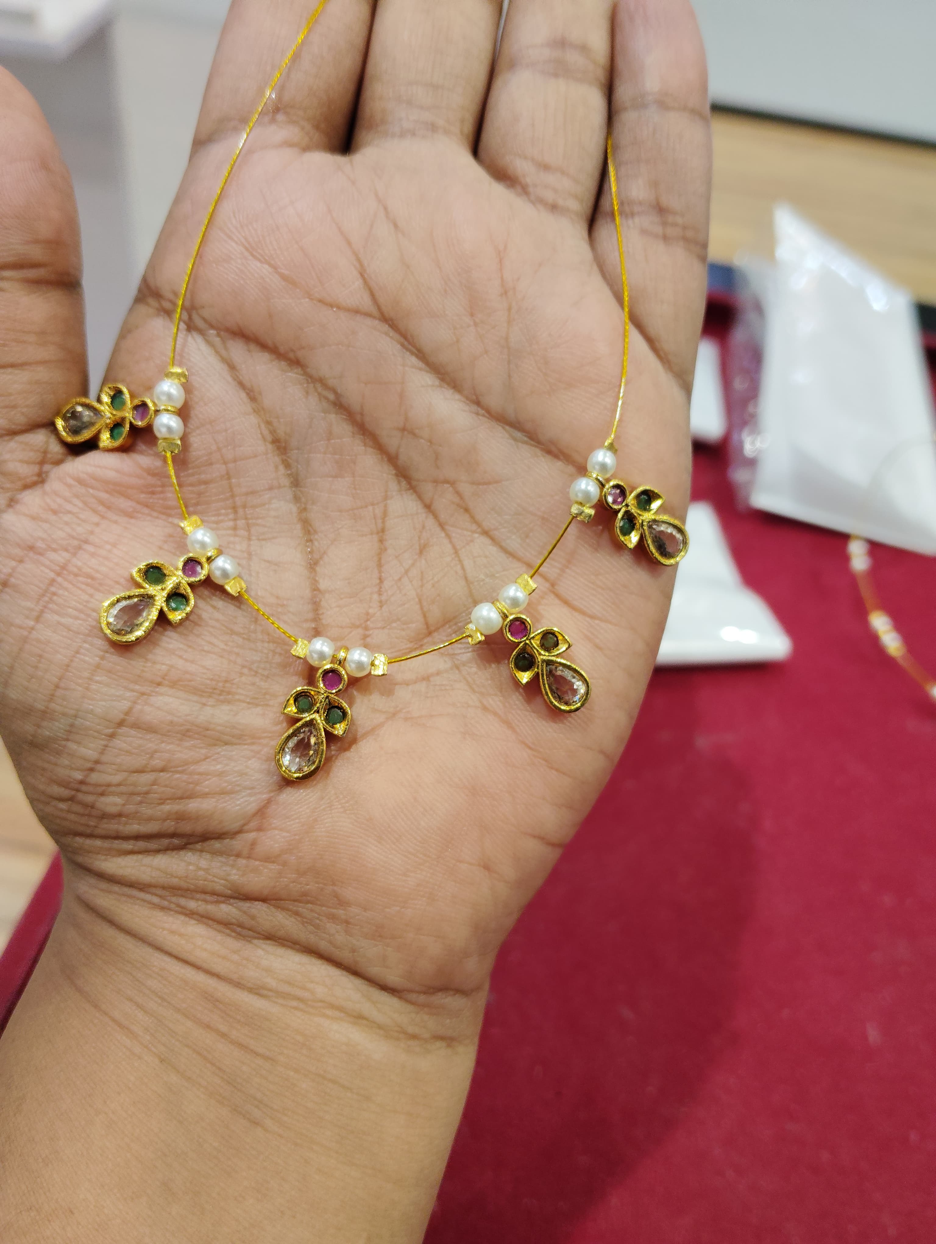 Thin yellow cord mangalsutra with teardrop and floral pendants and white bead spacers