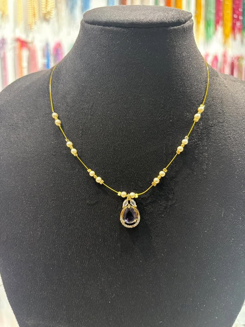 Delicate mangalsutra with fine gold-tone chain, spaced round beads and a teardrop dark pendant with halo